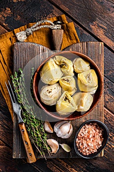 Appetizer Artichoke hearts pickled in olive oil with herbs and spices Wooden background. Top view
