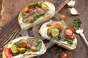 Appetizer bruschetta with chopped vegetables, Mascarpone and pesto sauce on ciabatta . rustic weathered wood background