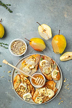 Appetizer bruschetta with pear, honey, walnut and thyme, New Years Eve or Christmas party, vertical image. top view. place for