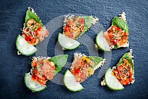 Appetizer canape with chopped vegetables and sesame on stone slate background close up.