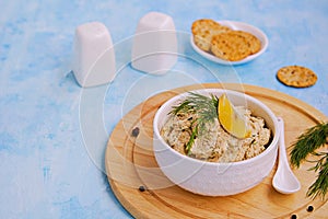 Appetizer, fish pate from mackerel, boiled eggs and onions in a white ceramic bowl on a blue concrete background. Served with