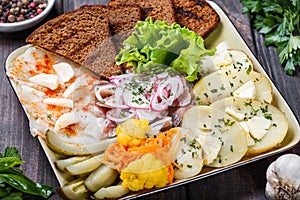 Appetizer platter, baked potato, delicious sliced pork fat with spices, sliced smoked fish with onions, pickles and bread