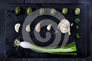 Appetizer set on wooden board. With olives,parsley,garlic. Top view. Dark background.