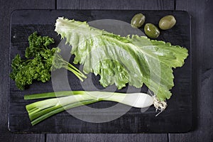 Appetizer set on wooden board. With olives,parsley,garlic. Top view. Dark background.