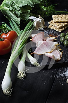 Appetizer set on wooden board. With olives,parsley,tomato,garlic. Top view. Dark background.