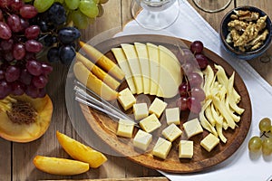 An appetizer of various types of cheese, grapes and walnuts, served with wine. Rustic style.