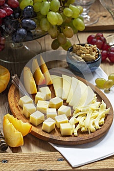 An appetizer of various types of cheese, grapes and walnuts, served with wine. Rustic style.