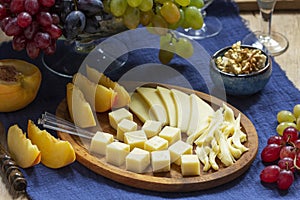 An appetizer of various types of cheese, grapes and walnuts, served with wine. Rustic style.