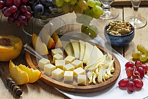 An appetizer of various types of cheese, grapes and walnuts, served with wine. Rustic style.