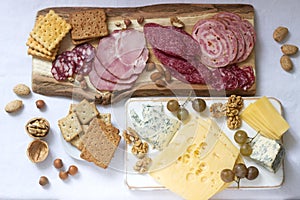 Appetizer of various types of sausages, meats, cheeses and crackers on a wooden board, served to wine