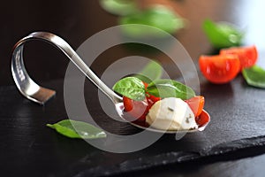 Appetizers with mozzarella and tomato on spoon - selective focus