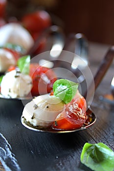 Appetizers with mozzarella and tomato on spoon - selective focus