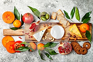 Appetizers table with antipasti snacks. Cheese variety board over grey concrete background. Top view, flat lay.