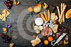 Appetizers table with italian antipasti snacks. Cheese and charcuterie variety board over rustic wooden background.