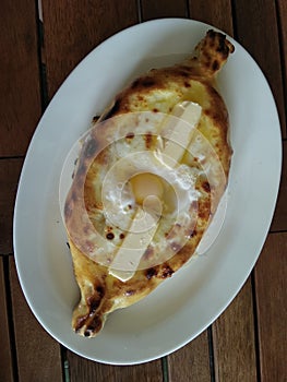 Appetizing Adzharian khachapuri with egg and butter.