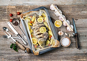 Appetizing baked fish with lemons, topview