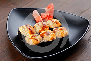 Appetizing baked hot sushi rolls. Set sushi on a plate with ginger.