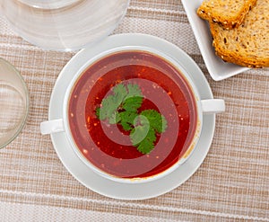 Appetizing beetroot soup with beef decorated by greens served in bowl