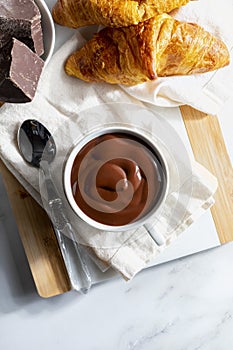 Appetizing breakfast with a delicious cup of thick, drinkable hot chocolate, along with croissants. Homemade look.