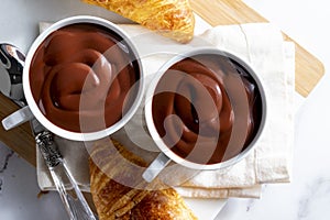 Appetizing breakfast with two delicious cups of thick, drinkable hot chocolate, along with croissants. Homemade look