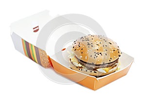 Appetizing burger in craft paper packaging. Delicious garbage food. Isolated on a white background. Close-up