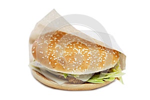 Appetizing burger in craft paper packaging. Delicious garbage food. Isolated on a white background. Close-up