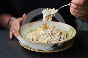 Appetizing carbonara paste with chicken improperly wound on fork. Spaghetti inaccurately hanging and falling from fork