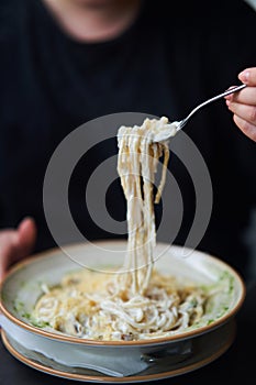 Appetizing carbonara paste with chicken improperly wound on fork. Spaghetti inaccurately hanging and falling from fork