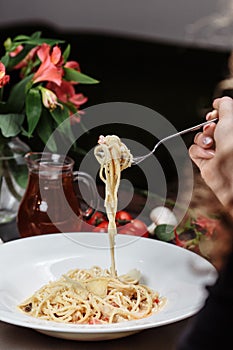 Appetizing carbonara paste with chicken improperly wound on fork. Spaghetti inaccurately hanging and falling from fork. Close up