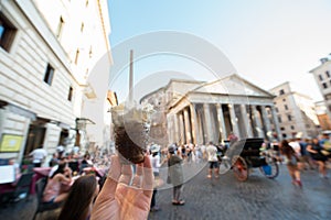 Appetizing coffee ice cream in female hand over Pantheon city view, Rome, Italy