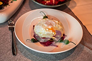 Appetizing cooked egg on a top of chopped ham and roasted peppers