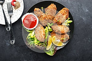 Appetizing crispy chicken wings breaded with bread crumbs with lettuce, sauce, lemon, microgreens in a plate on the