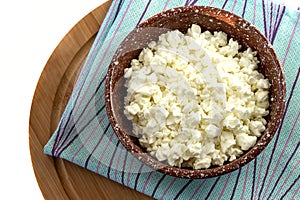 Appetizing crumbly fresh cottage cheese for breakfast in a clay bowl.