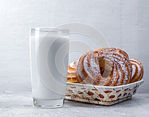 Appetizing custard rings and a glass of milk on a white background