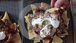 Appetizing dish on a plate: corn chips nachos with fried minced meat and guacamole, salsa, jalapeno top view. Homemade