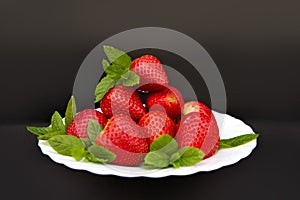 Appetizing, freshness of strawberries is emphasized by the contrast of black, the decor of mint leav