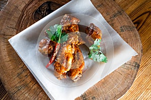 Appetizing fried chicken wings in sauce on a wooden tray. The concept of food and serving, food in bars and restaurants