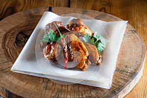 Appetizing fried chicken wings in sauce on a wooden tray. The concept of food and serving, food in bars and restaurants