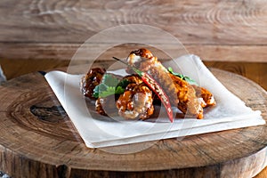 Appetizing fried chicken wings in sauce on a wooden tray. The concept of food and serving, food in bars and restaurants