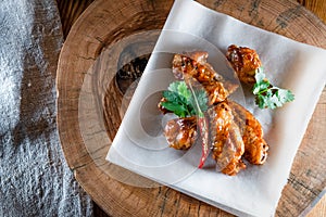 Appetizing fried chicken wings in sauce on a wooden tray. The concept of food and serving, food in bars and restaurants