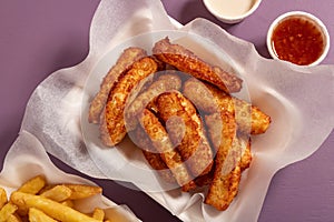 Appetizing gold fried halloumi and potatoes portions with dips on soft violet background