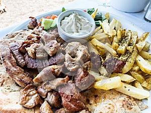 Appetizing Greek dish with meat, vegetable fries and the famous sauce