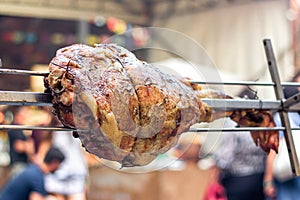 Appetizing grilled pork on the spit. Roasted leg of porkon traditional barbecue. Prepared of a ram pig baked pork meat Street food