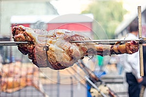 Appetizing grilled pork on the spit. Roasted leg of porkon traditional barbecue. Prepared of a ram pig baked pork meat Street food
