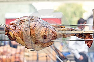 Appetizing grilled pork on the spit. Roasted leg of porkon traditional barbecue. Prepared of a ram pig baked pork meat Street food