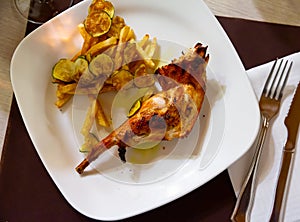 Grilled rabbit leg with fried potato and zucchini chips