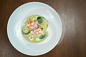 Appetizing and healthy green pea cream soup with broccoli and salmon cooked in a smoker on a wooden background. Top view