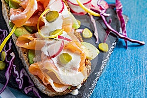 Appetizing and healthy smoked salmon with avocado, vegetables radish, lemon, red cabbage, pickle and yogurt sauce on toasted