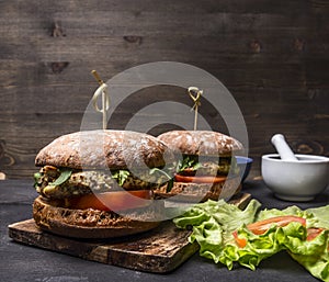 Appetizing homemade burgers with chicken in mustard sauce with arugula and herbs on a cutting board text area on wooden rusti