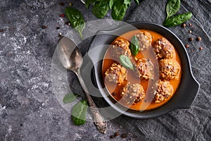 Appetizing homemade meatballs with tomato sauce and spinach served in a plate on a dark stone table Copyspace Top view